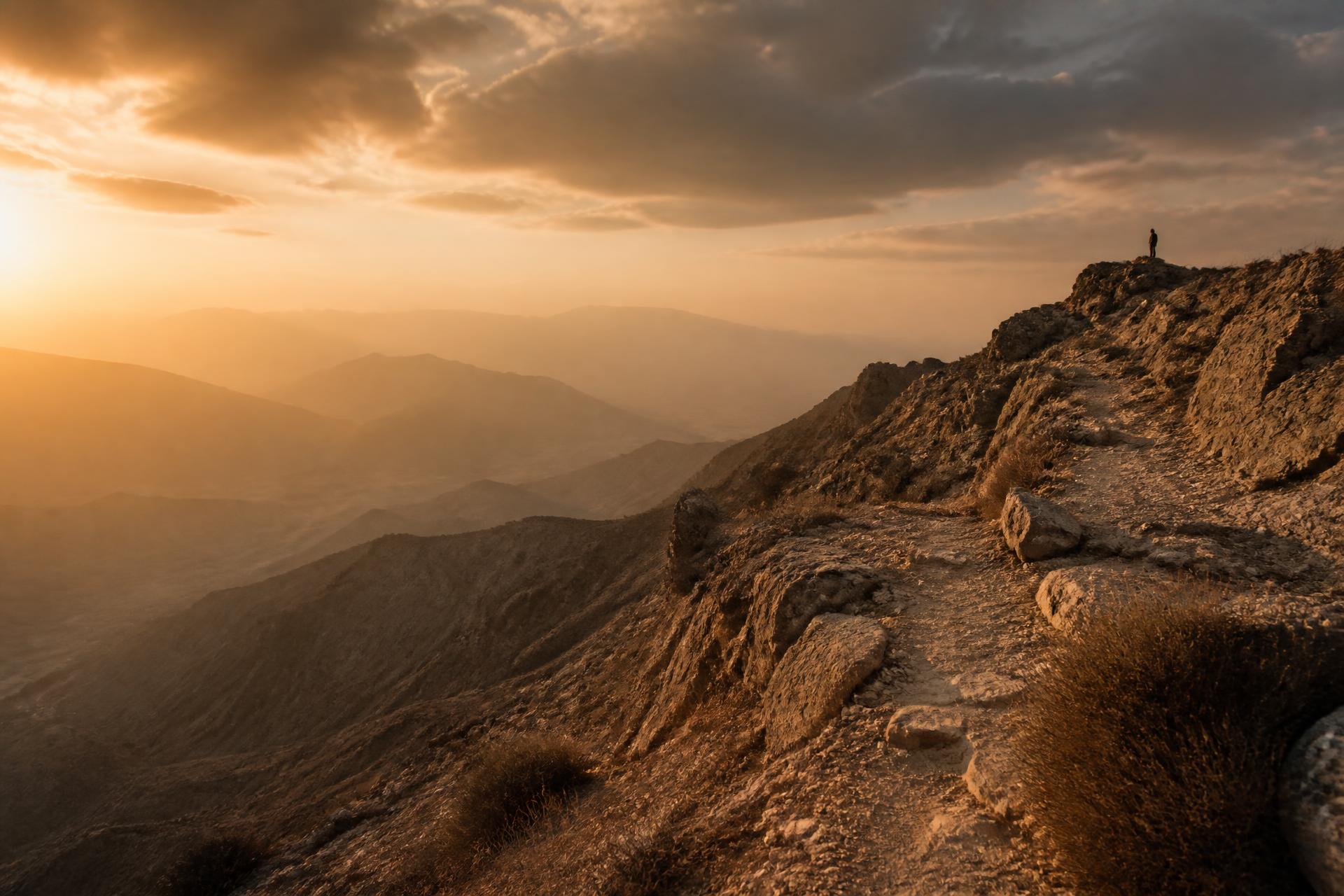A hiker on a mountain ridge in the UAE at golden hour